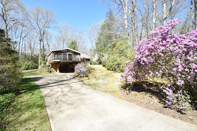 view of property exterior featuring concrete driveway and a wooden deck