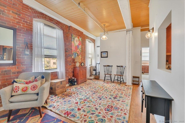 sitting room with wooden ceiling, wood finished floors, and brick wall