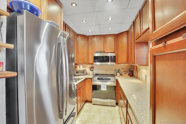 kitchen with tasteful backsplash, stainless steel appliances, light countertops, and brown cabinets
