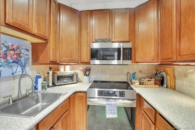 kitchen featuring a toaster, a sink, stainless steel appliances, and light countertops