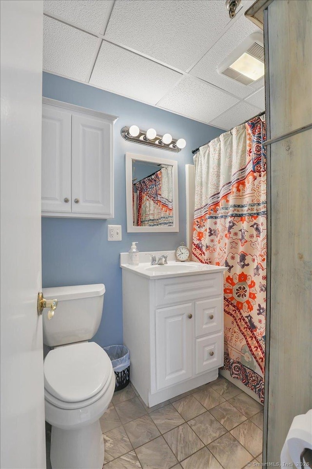 bathroom with a shower with curtain, toilet, vanity, visible vents, and a paneled ceiling