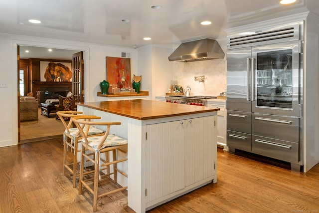 35 Old Redding Rd, Easton, CT 06612 - kitchen with built in refrigerator, wall chimney range hood, butcher block countertops, wood finished floors, and recessed lighting