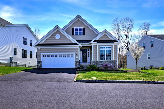 craftsman house with a front yard, a standing seam roof, stone siding, aphalt driveway, and an attached garage