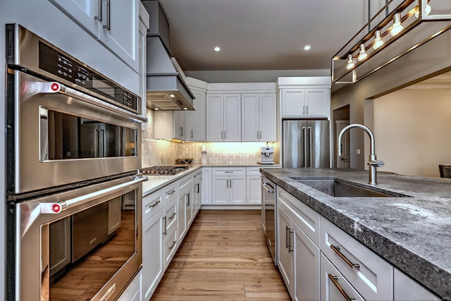 kitchen with tasteful backsplash, white cabinets, a sink, appliances with stainless steel finishes, and recessed lighting