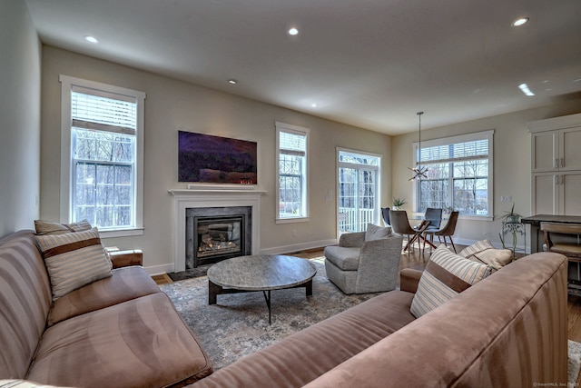 living room with a fireplace, recessed lighting, wood finished floors, and baseboards