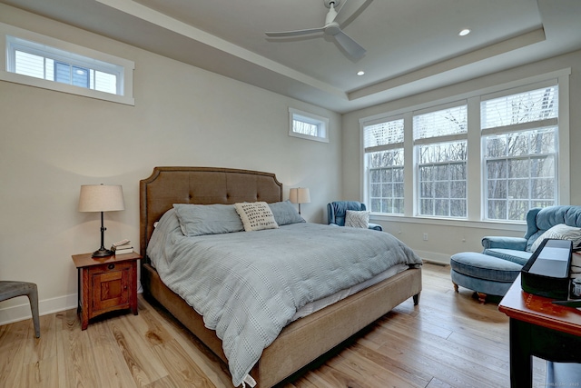 bedroom featuring a raised ceiling, light wood-type flooring, recessed lighting, and baseboards