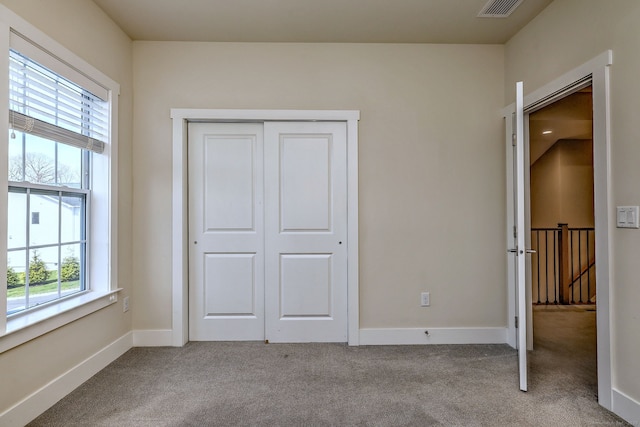 unfurnished bedroom featuring a closet, visible vents, carpet floors, and baseboards