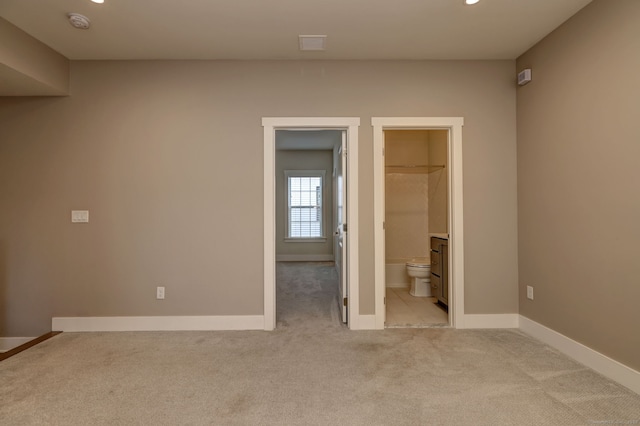 unfurnished bedroom featuring recessed lighting, ensuite bath, light colored carpet, and baseboards