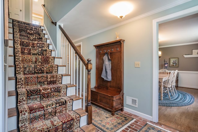 interior space with crown molding, baseboards, visible vents, and brick floor