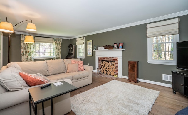 living area with visible vents, a fireplace, wood finished floors, baseboards, and ornamental molding