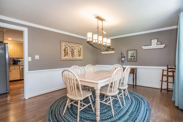 dining room featuring crown molding, wainscoting, and wood finished floors