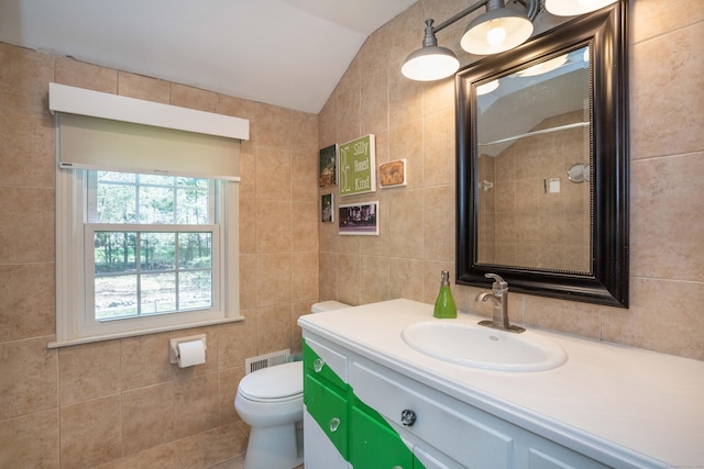 bathroom featuring vanity, vaulted ceiling, toilet, and tile walls