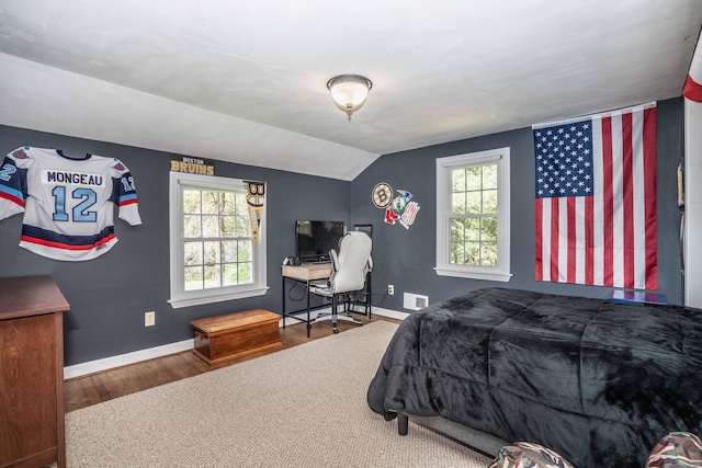 bedroom featuring visible vents, multiple windows, wood finished floors, and lofted ceiling
