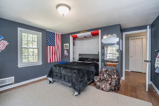bedroom with visible vents, baseboards, and wood finished floors