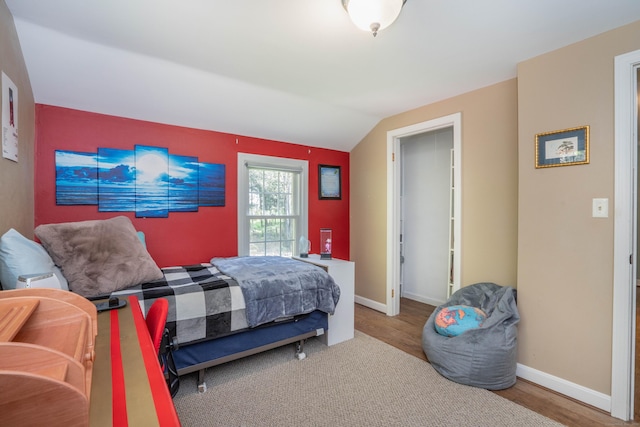 bedroom with baseboards, wood finished floors, and lofted ceiling