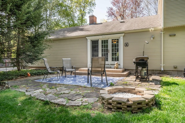 rear view of property featuring a patio area, a fire pit, and a chimney