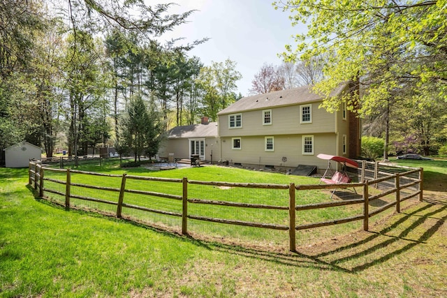 back of property with an outdoor structure, fence, a yard, and crawl space