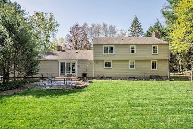rear view of property with a patio, a yard, and a chimney