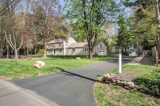 colonial inspired home with fence, a front lawn, and aphalt driveway