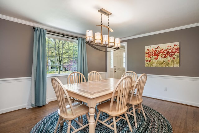 dining room with baseboards, ornamental molding, wood finished floors, and a chandelier