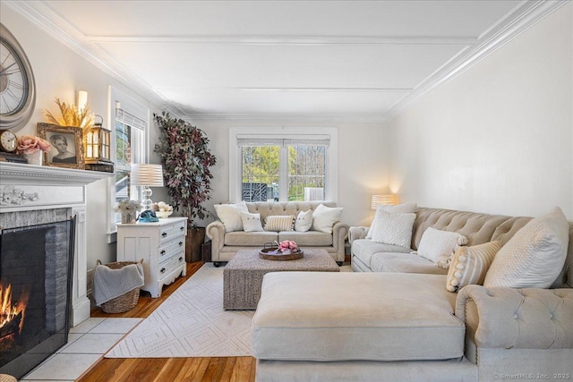 living area with light wood finished floors, a fireplace with flush hearth, and crown molding