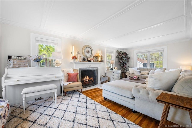 living room featuring crown molding, a fireplace with flush hearth, and wood finished floors
