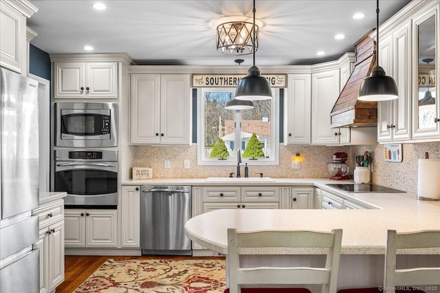 kitchen with white cabinetry, a sink, stainless steel appliances, light countertops, and dark wood finished floors