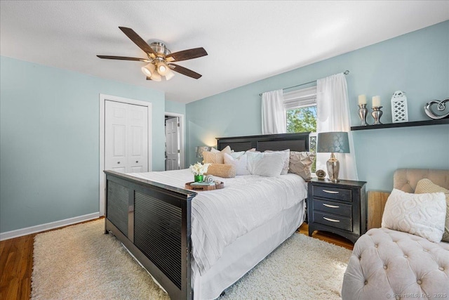 bedroom featuring baseboards, wood finished floors, ceiling fan, and a closet