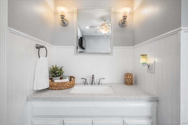 bathroom with a ceiling fan, wainscoting, and vanity