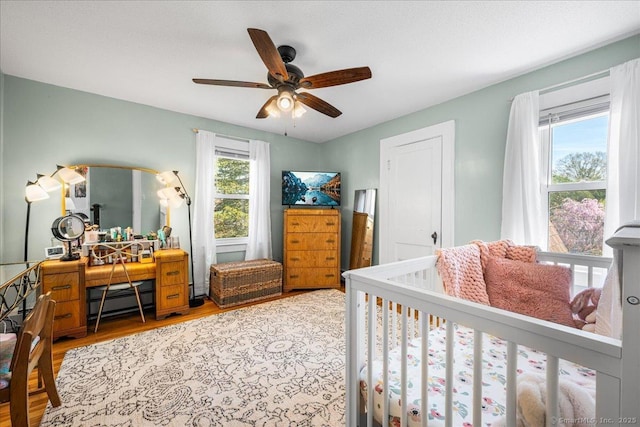 bedroom with baseboard heating, wood finished floors, and a ceiling fan