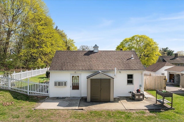 back of house featuring an outdoor structure, fence, a yard, and a patio area