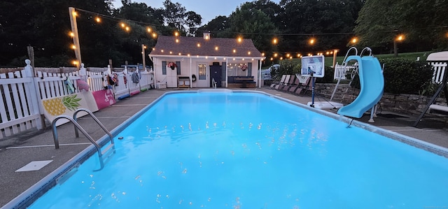 view of pool featuring an outdoor structure, a patio, a storage structure, a water slide, and fence