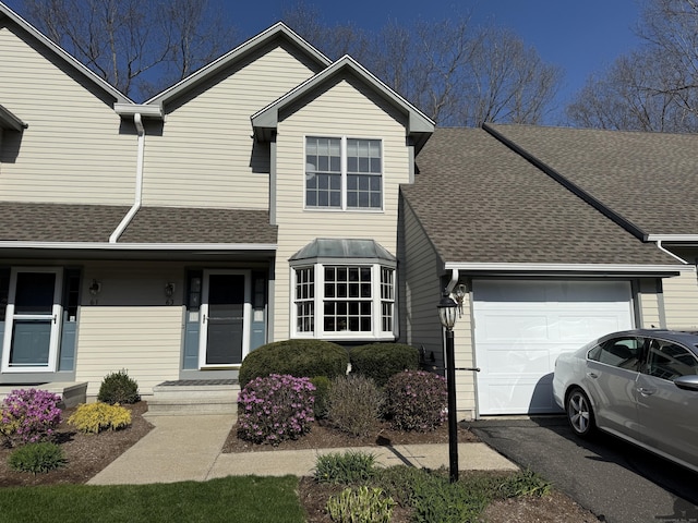 traditional-style home featuring driveway, a garage, and roof with shingles