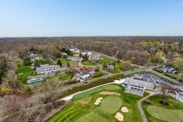 drone / aerial view with golf course view and a wooded view