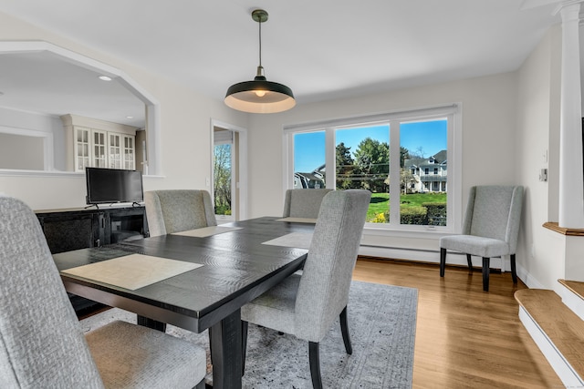 dining room featuring light wood-type flooring, recessed lighting, arched walkways, and a baseboard heating unit