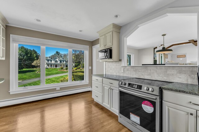 kitchen with a baseboard radiator, appliances with stainless steel finishes, backsplash, and a wealth of natural light
