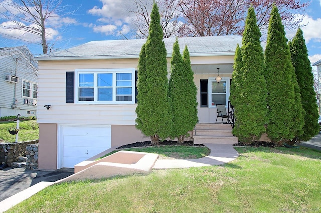 ranch-style home featuring covered porch, a front yard, an attached garage, and an AC wall unit