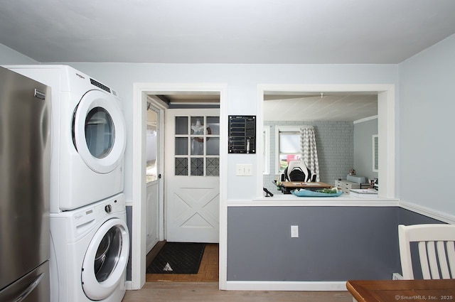 washroom featuring wood finished floors, stacked washer and dryer, and laundry area