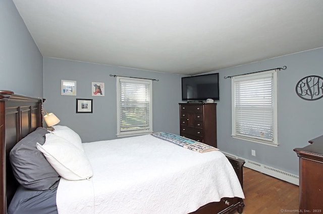 bedroom featuring a baseboard heating unit and dark wood finished floors