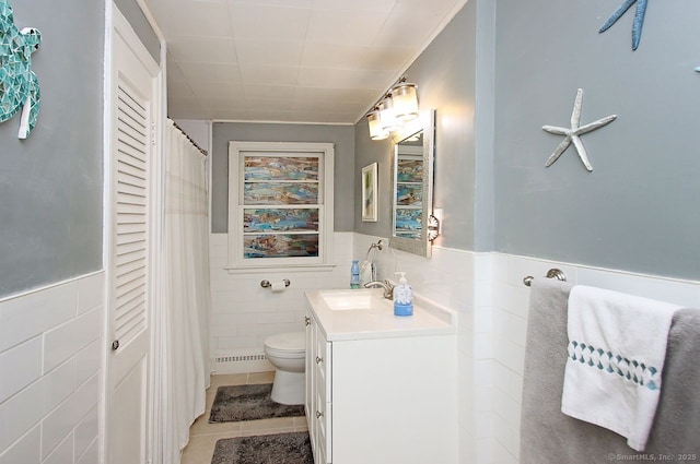 full bath featuring tile walls, vanity, tile patterned floors, toilet, and a wainscoted wall