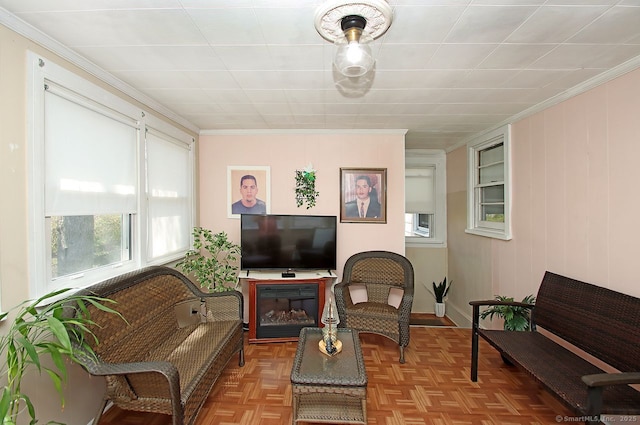 living area with ornamental molding, baseboards, and plenty of natural light