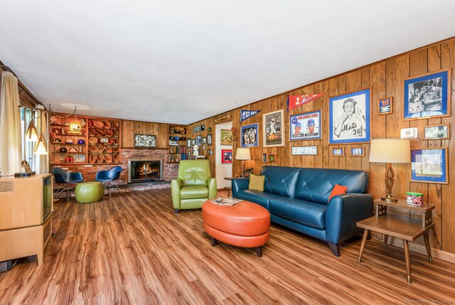 living room featuring wooden walls, a brick fireplace, and wood finished floors