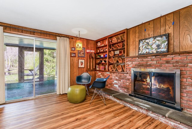 sitting room with wood walls, wood finished floors, and a fireplace