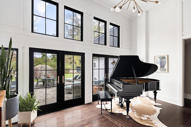 sitting room with a towering ceiling, hardwood / wood-style flooring, and french doors