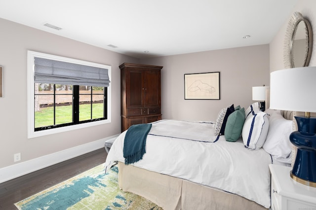 bedroom with wood finished floors, visible vents, and baseboards