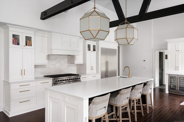 kitchen featuring a sink, high vaulted ceiling, high quality appliances, backsplash, and an island with sink