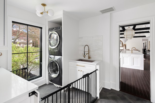 washroom with laundry area, a chandelier, a sink, visible vents, and stacked washer and clothes dryer