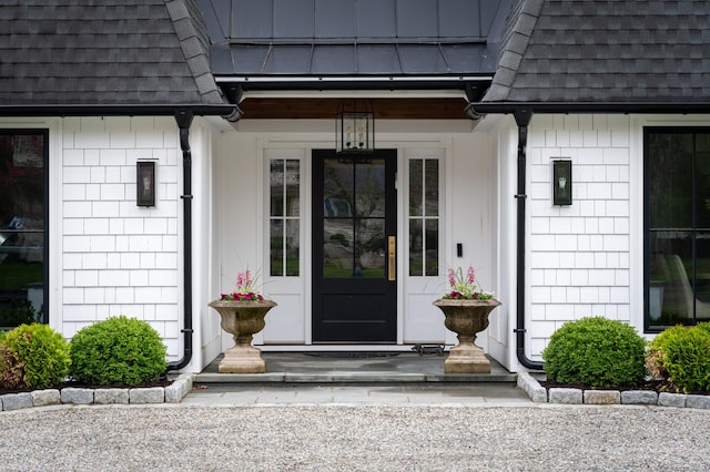 property entrance featuring covered porch and a shingled roof