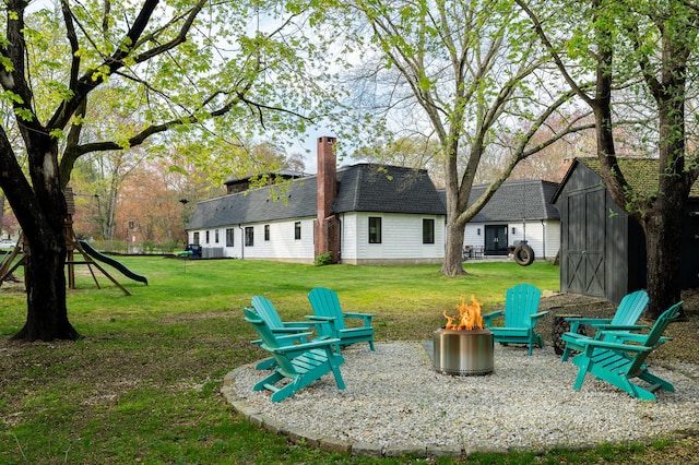 view of yard featuring a fire pit, a storage unit, central AC, and an outbuilding