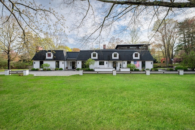 view of front of house with a chimney, a front lawn, and roof with shingles